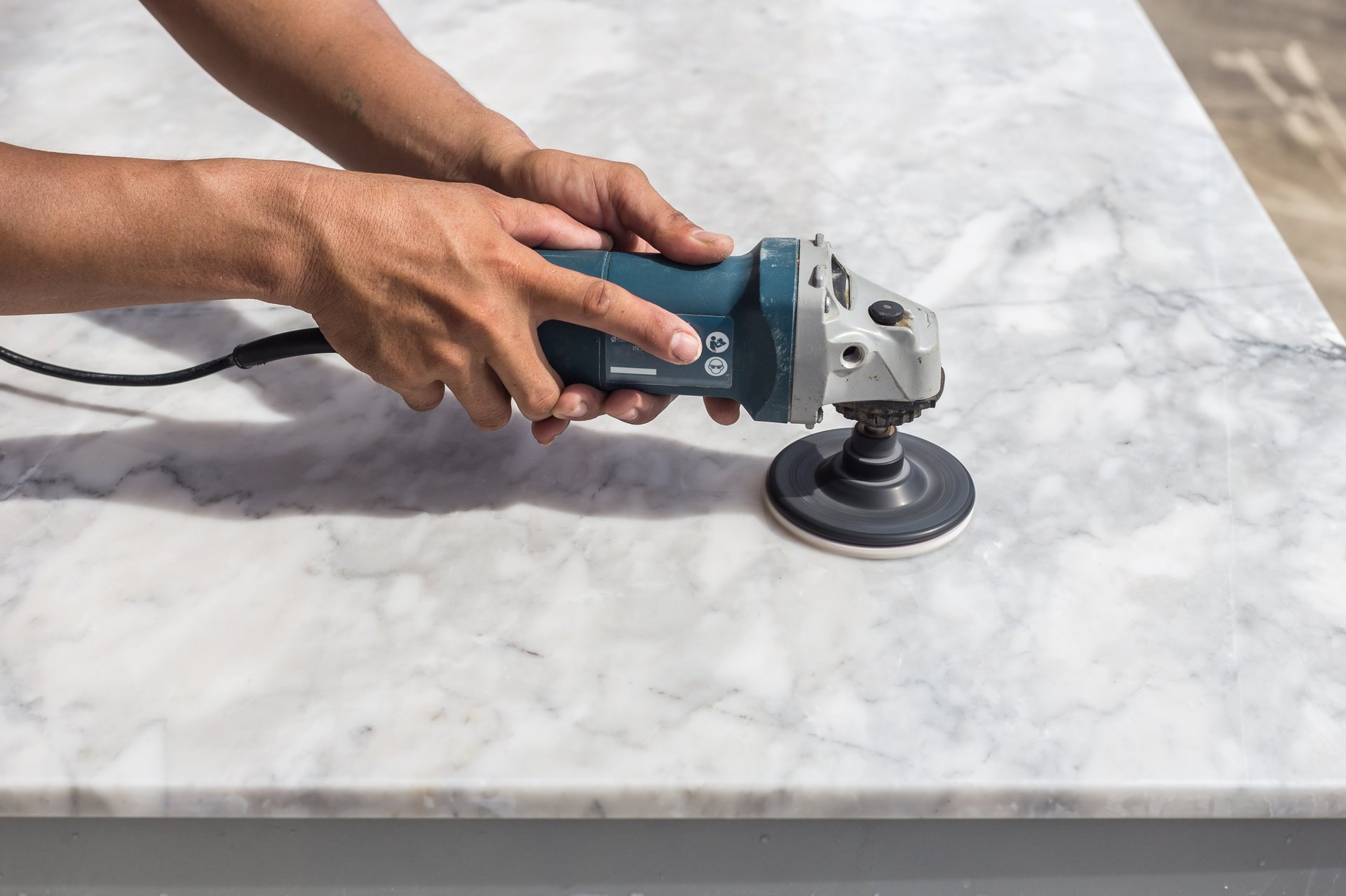 Professional marble stone restoration technician polishing a marble countertop